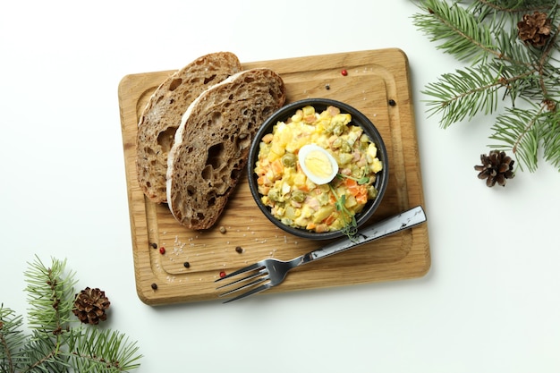 Weihnachtskonzept von leckerem Essen mit Olivier-Salat auf weißem Hintergrund
