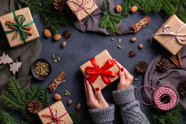 Weihnachtskonzept weibliche Hände, die handgemachte umweltfreundliche Geschenkboxen verpacken