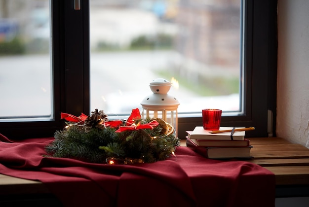 Weihnachtskränze, Bücher, Kerzen, Laterne am Fenster