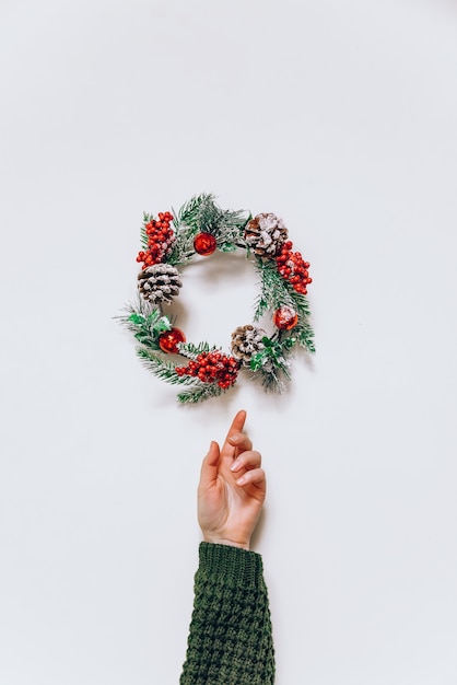 Foto weihnachtskranz aus fichte und frauenhand im minimalistischen stil.