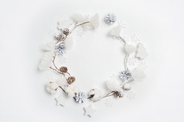 Weihnachtskranz aus hölzernen Schneeflocken, Baumwollblumen, Tannenzapfen und weißen Blumenpompons.
