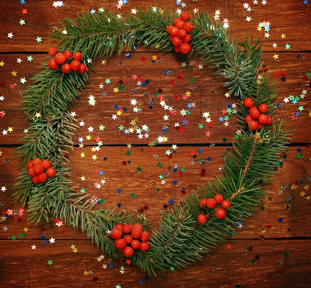 Weihnachtskranz aus Tannenzweigen auf dem hölzernen Hintergrund