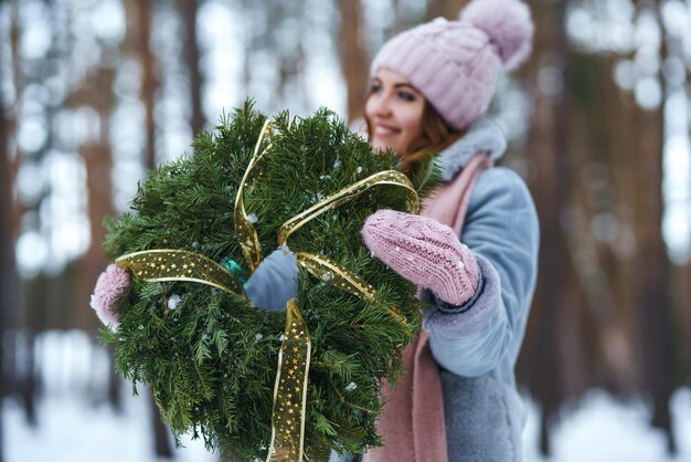 Weihnachtskranz in schönen Frauenhänden im Schneewald. saisonale Feiertage, schmücken. Weihnachten