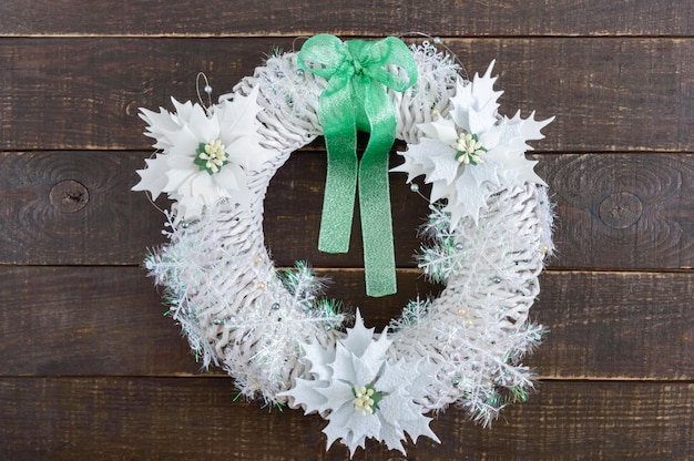 Weihnachtskranz in weißer Farbe mit festlichen Dekorationen auf Holzhintergrund. Hausgemachtes festliches Kunsthandwerk