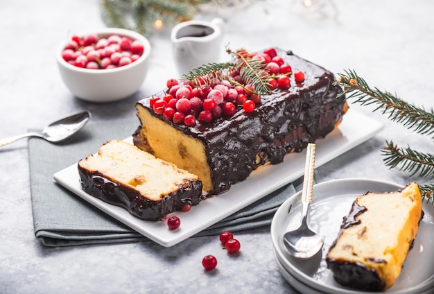 Weihnachtskuchen mit Moosbeeren und Weihnachtsdekorationen auf einer hellen Oberfläche.