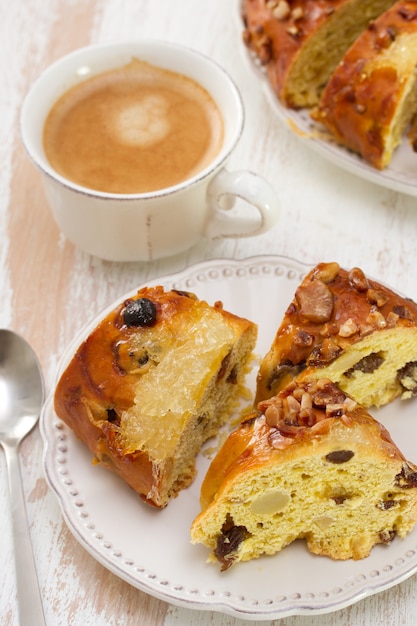 Weihnachtskuchen mit trockenen Früchten auf weißer Platte mit Tasse Kaffee