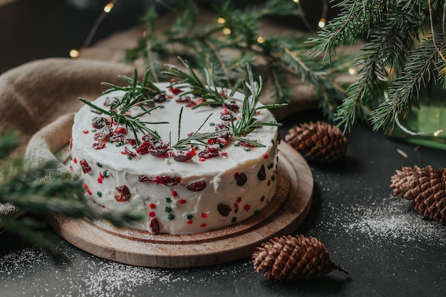 Foto weihnachtskuchen mit weißer käsecreme, dekoriert mit preiselbeeren und rosmarin.