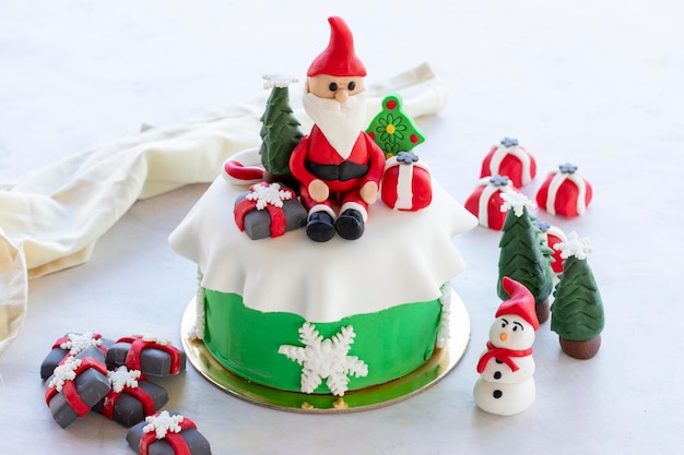 Weihnachtskuchen mit Zuckerpaste zubereitet Mit Weihnachtsmann-Weihnachtsbaum und Geschenkfiguren darauf