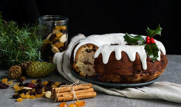 Weihnachtskuchen, verziert mit Weihnachtsstechpalme, Fruchtkuchen auf dem grauen Stein