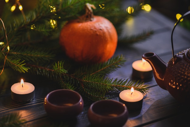 Weihnachtskürbise auf Holztisch mit Lichtern