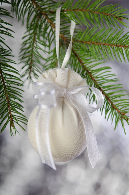 Weihnachtskugel eingewickelt in medizinische Maske mit weißem Band Neujahrsdekoration