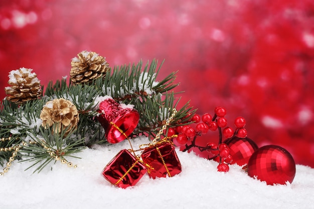 Weihnachtskugel und grüner Baum im Schnee auf Rot