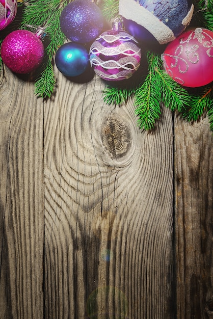 Weihnachtskugeln liegen auf Tannenzweigen auf einem hölzernen Hintergrund