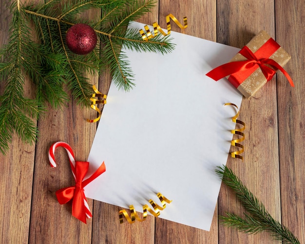 Weihnachtskugeln Tannenzweige Geschenkbälle für den Weihnachtsbaum Zuckerstangen Papier für Text auf einem braunen Holztisch Weihnachten aus Holz Hintergrund Neujahr Weihnachten Winterurlaub Textfreiraum