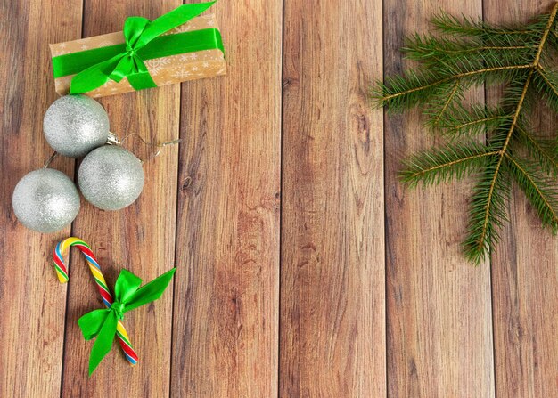 Weihnachtskugeln Tannenzweige Geschenkbälle für den Weihnachtsbaum Zuckerstangen Papier für Text auf einem braunen Holztisch Weihnachten aus Holz Hintergrund Neujahr Weihnachten Winterurlaub Textfreiraum