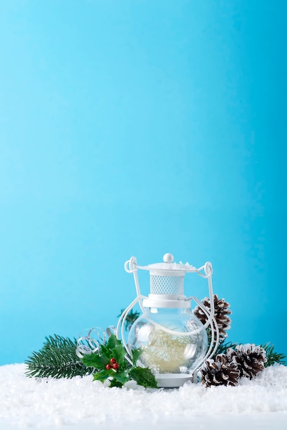 Weihnachtslaterne auf Schnee mit Tannenzweig und Winterdekoration auf Blau. Feiertags-Weihnachtskonzept.