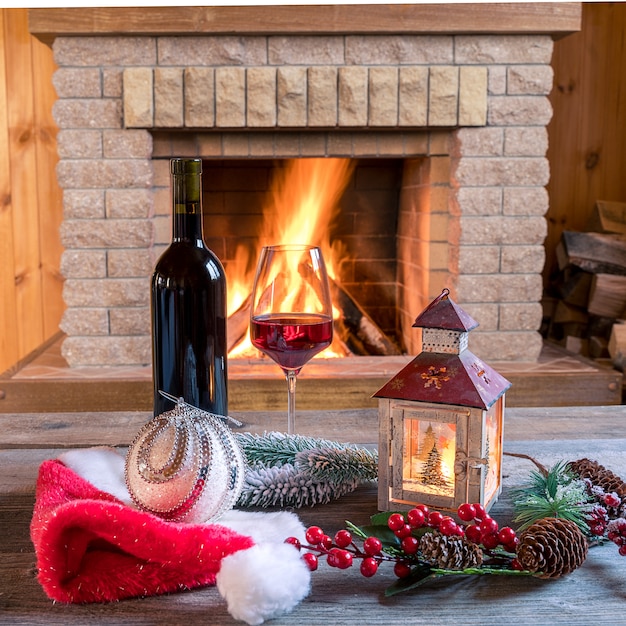 Weihnachtslaterne, Rotwein und Weihnachtsdekorationen nähern sich gemütlichem Kamin, im Landhaus.