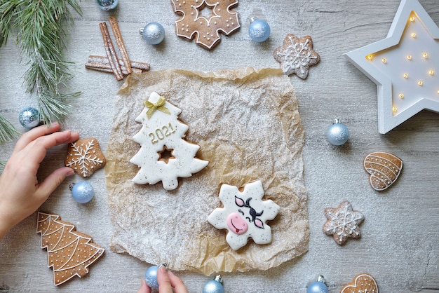 Weihnachtslebkuchen in Glasur in Form von Weihnachtsbäumen mit 2021, Weihnachtssymbolen 2021, auf einem Tisch mit Neujahrsdekor, horizontal.