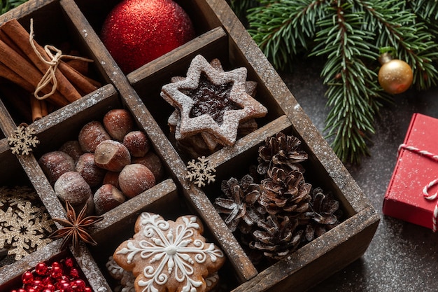 Weihnachtslebkuchen, Kekse, Nüsse und Weihnachtsdekorationen in der Holzkiste mit Tannenbaum und Geschenken.