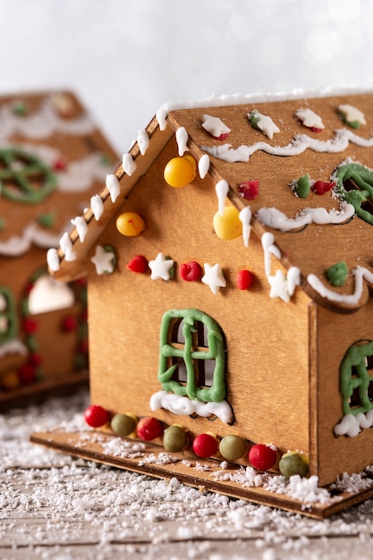 Weihnachtslebkuchenhaus verziert mit Bonbons und Glasur auf Holztisch