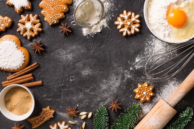 Weihnachtslebkuchenhintergrundplätzchen mit Zutatenkochen, frohes neues Jahr-Feiertagskonzept auf dunkler Textur, Kopienraum