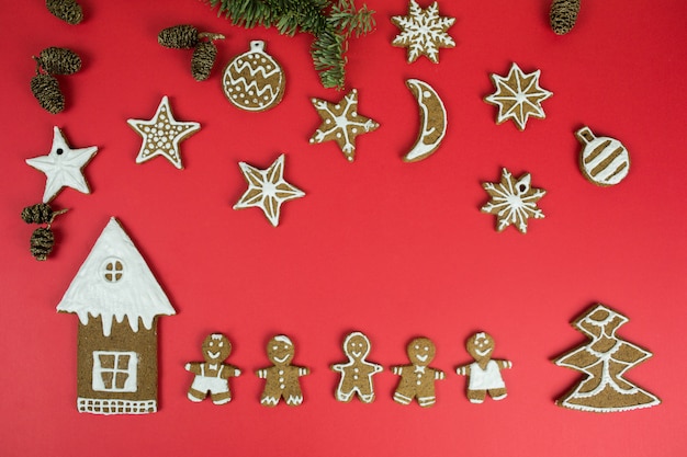 Weihnachtslebkuchenplätzchen mit Dekorationen des neuen Jahres auf rotem Hintergrund. Feiertage, Weihnachten, Nachtisch, Lebensmittel des neuen Jahres, Gestaltungselementkonzept