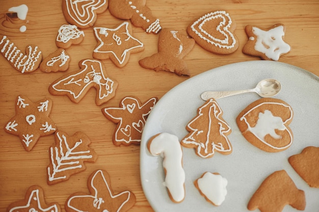 Weihnachtslebkuchenplätzchen mit Zuckerguss auf Teller und Tisch flach gelegt Einfach dekorierte Kekse