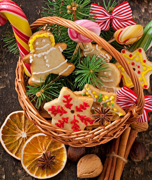 Weihnachtslebkuchenplätzchen und -lutscher in einem Korb auf altem hölzernem Hintergrund