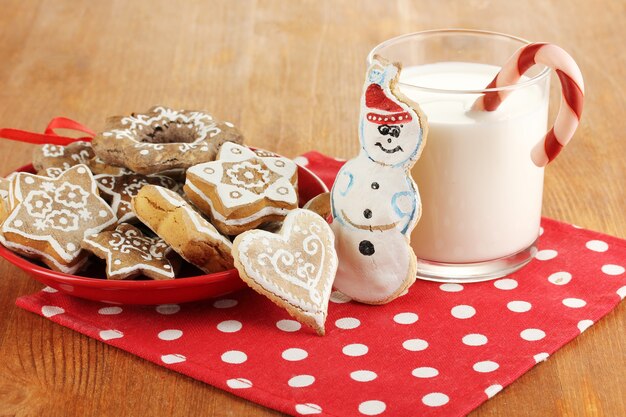 Weihnachtsleckereien auf Teller und Glas Milch auf Holztischnahaufnahme