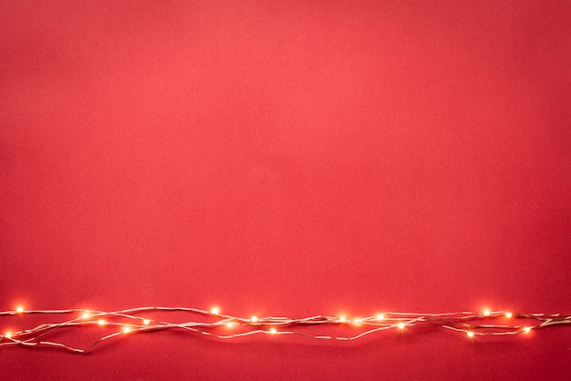 Weihnachtslichtgirlandenrand über rotem hintergrund.