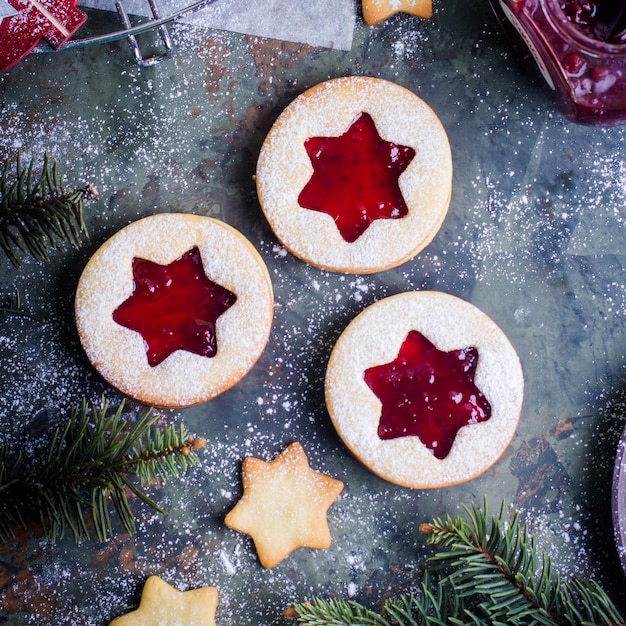 Weihnachtslinzer-Plätzchen mit Himbeermarmelade auf Hintergrund der grünen Tabelle.