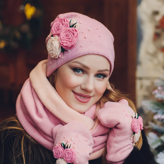 Weihnachtsmädchen, welches die gestrickte warme Mütze und Handschuhe, lokalisiert auf Grau trägt
