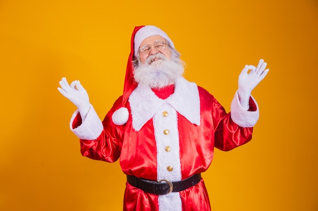 Weihnachtsmann, der auf gelbem Hintergrund meditiert. Zen Santa auf der Suche nach spirituellem Frieden