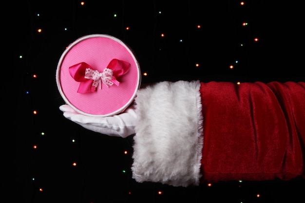 Weihnachtsmann-Hand, die Geschenkbox auf hellem Hintergrund hält