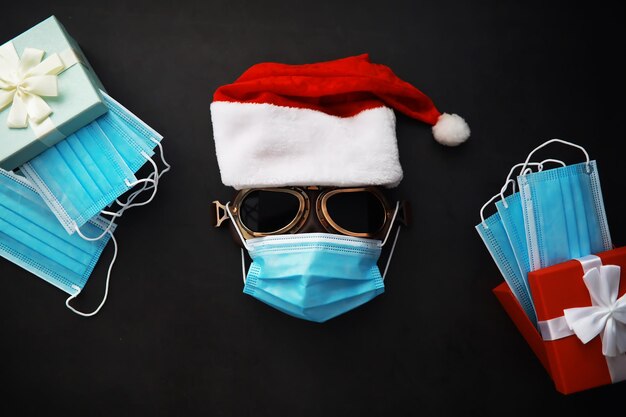 Weihnachtsmann-Hut, Brille und Nase mit Gesichtsmaske auf rotem Grund. Weihnachts- oder Neujahrsfeierkonzept. Weihnachtsrentier aus schützender Gesichtsmaske und Dekorationen. Gesundheitskonzept.