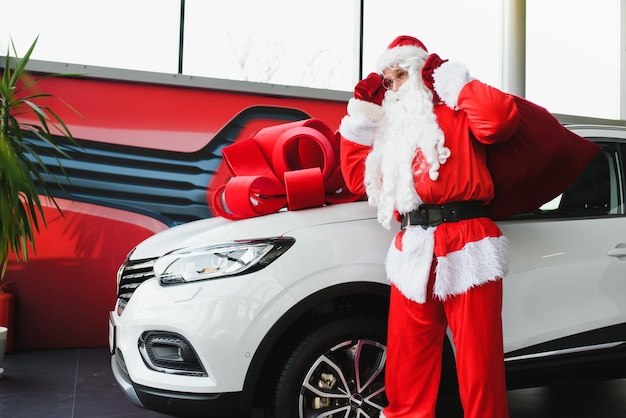 Weihnachtsmann in der Nähe eines Neuwagens in einem Autohaus.