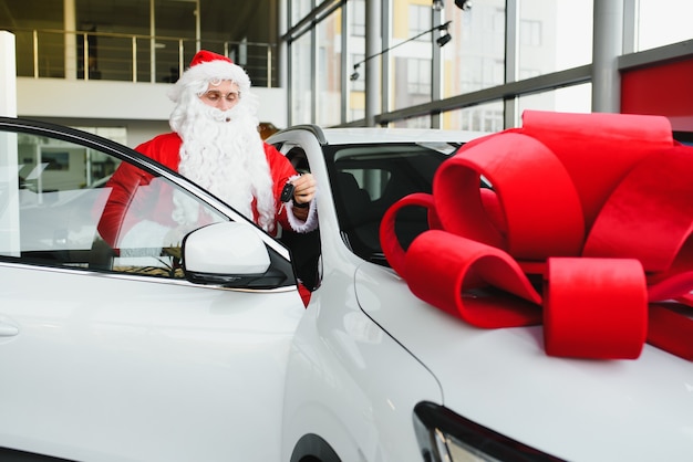 Weihnachtsmann in der Nähe eines Neuwagens in einem Autohaus.