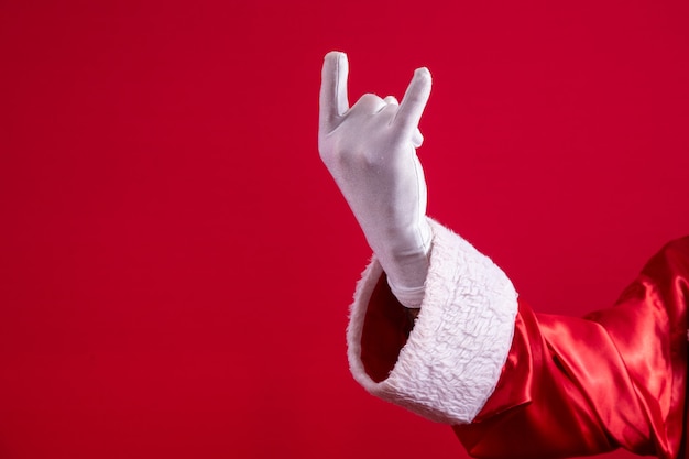 Weihnachtsmann macht Rock n Roll Schild mit Händen und rotem Hintergrund.