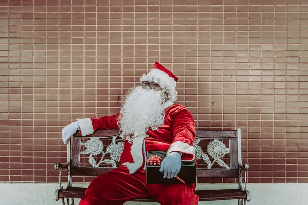 Weihnachtsmann mit Geschenkbox sitzen auf der BankThailänderGlück für Kinder geschicktFrohe WeihnachtenWillkommen im Winter