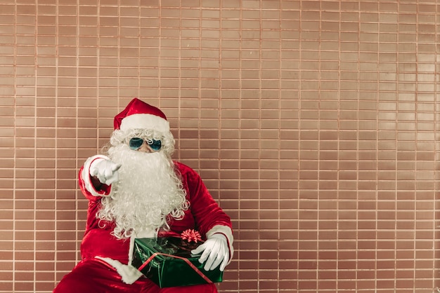 Weihnachtsmann mit Geschenkbox sitzen auf der BankThailänderGlück für Kinder geschicktFrohe WeihnachtenWillkommen im Winter