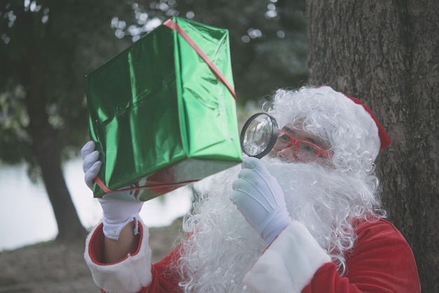 Weihnachtsmann mit Geschenkbox sitzen unter BaumThailänderGesendetes Glück für KinderFrohe WeihnachtenWillkommen im Winter