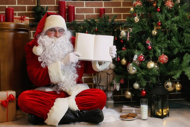 Weihnachtsmann mit Geschenken sitzt neben einem Weihnachtsbaum