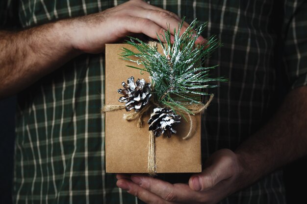 Weihnachtsmanneshände, die selbst gemachte Weihnachtsgeschenkdunkelheit halten