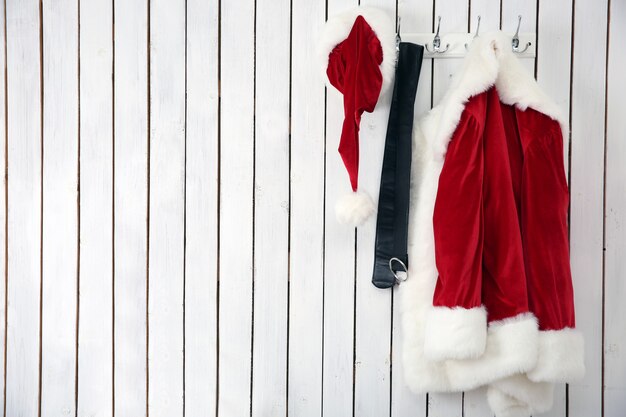 Weihnachtsmannjacke, Hut und Gürtel an einer weißen Holzwand