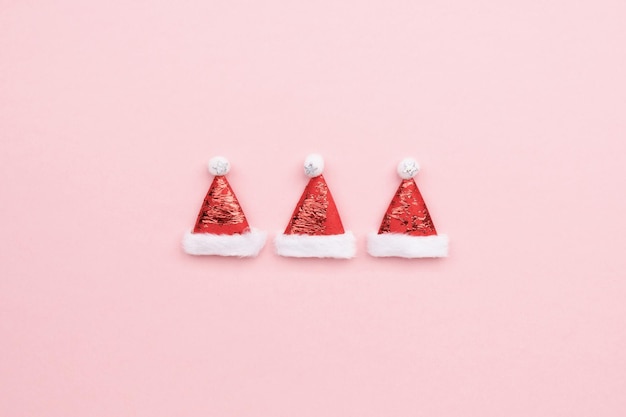 Weihnachtsmannmützen auf rosa Hintergrund, minimalistischer Weihnachtshintergrund mit Kopierraum
