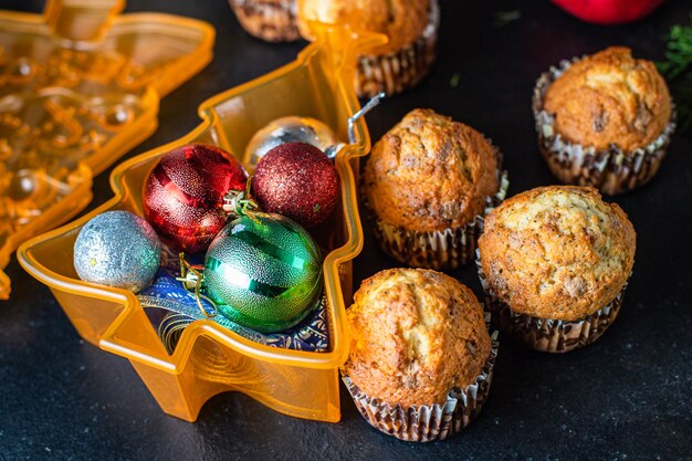 Weihnachtsmuffins mit Dekorationen auf schwarzem Tisch