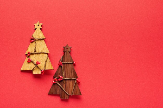 Weihnachtsmuster aus hölzernen Weihnachtstannenbaumspielzeugen, Schneeflocken und Sternen auf Rot.