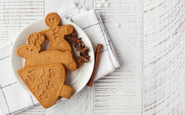 Weihnachtsoberfläche mit Ingwerplätzchen und Gewürzen auf einer hellen Holzoberfläche