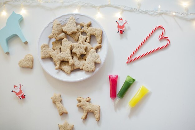 Weihnachtsplätzchen auf einem weißen Teller mit bunten Zuckerglasur Weihnachtsplätzchen Hintergrund Gebackene Kekse Glasur in Rohren Zuckerstangen und Lichter