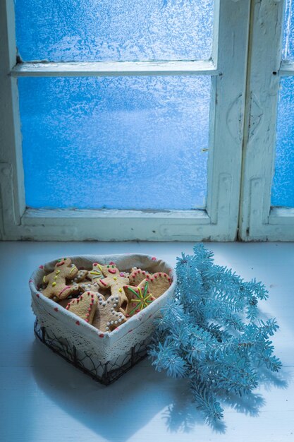 Weihnachtsplätzchen auf weißem Tisch und gefrorenem Fenster